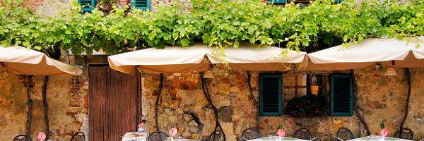 Cafe tables and chairs outside a quaint stone building in Tuscany, Italy